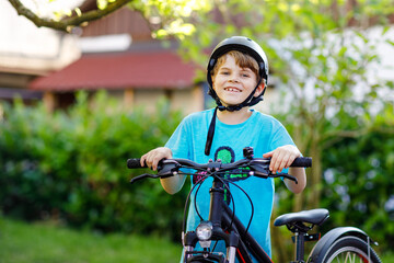 Happy school kid boy having fun with riding of bicycle. Active healthy child with safety helmet making sports with bike in nature. Safety, sports, leisure with kids concept