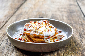 American pancakes with nuts, maple syrup and coconut cream on wooden table. Tasty sweet food for breakfast, brunch or lunch in outdoor cafe or restaurant