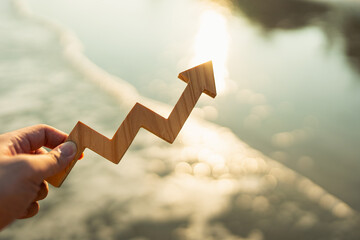 Businessman holding arrow up with sea waves in the background, concept of investment with uncertainty and risk but high return.