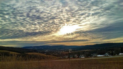 Obraz premium Serene Sunset over Rolling Hills and Small Town