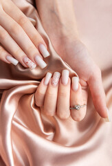 Woman showing stylish white nails with red glitter and diamond ring on silk fabric