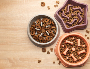 Slow feeder dog bowls with various dry food on wooden table