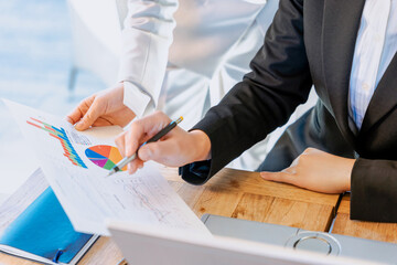 数値やグラフといったデータをチームワークで分析する2人の女性の手元