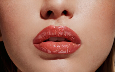 Naklejka premium Close-up of lips with coral red lipstick or lip gloss