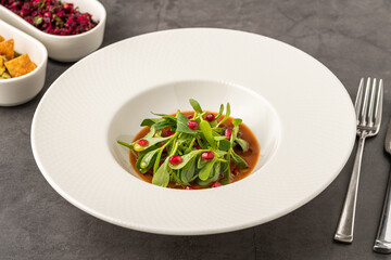 Purslane salad with olive oil and pomegranate in a white porcelain plate