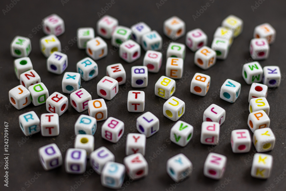 Fototapete a colorful scattering of letter cubes spills across a dark surface, creating a playful and whimsical