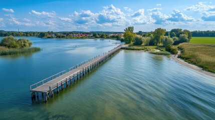 Fototapeta premium Aerial View of a Serene Jetty Surrounded by Lush Greenery and Calm Waters, Under a Bright Blue Sky with Fluffy Clouds