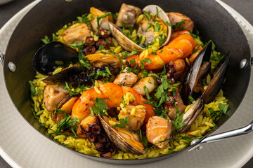 Top view of traditional Spanish seafood paella with rice, mussels and shrimps in a pan on stone table