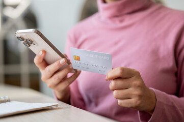 A close-up of a woman enjoys shopping online through her smartphone while relaxing in a cafe.