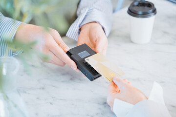 店舗でのショッピングをクレジットカードのタッチ決済で行う女性の手元
