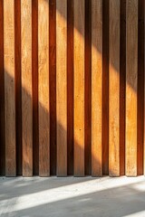 A close-up of vertical wooden slats in an outdoor building wall, illuminated by the morning sun casting long shadows on the concrete floor. 