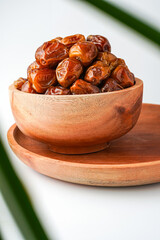 Dates fruit sukari or kurma sukari, in wooden bowl isolated on white background