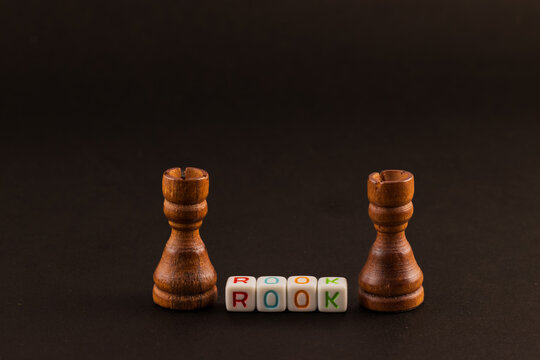 Two chess ROOCKs stand tall against a dark backdrop, facing each other in silent anticipation. The word "ROOCK" is spelled out below, highlighting their role in the game of strategy.