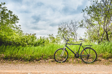 Parked Bike on the side of a Gravel Road with Field in Background