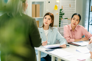 A group of professionals attentively listening to a speaker in a modern office environment, engaged in a discussion or presentation.