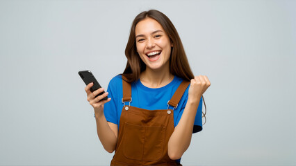 Young Caucasian woman wearing a blue t-shirt and and brown overalls are happy while holding smartphone 02