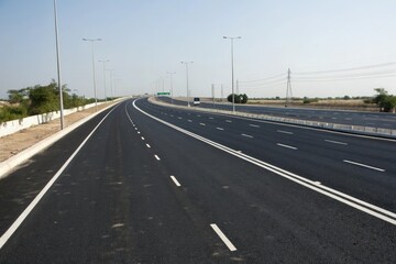 Fototapeta premium Wide-angle shot of black asphalt road with multiple lanes and white dividing lines, urban transportation, road network, highway