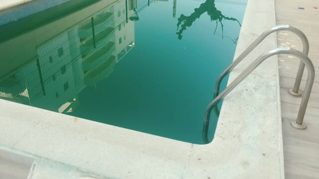 Swimming pool with dirty green water close-up.