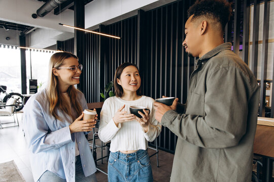 Multi-ethnic colleagues enjoying coffee break in modern office