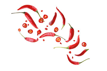 Obraz premium Hot chili peppers in motion with scattered seeds and chili flakes.
