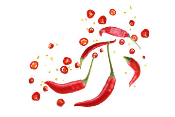 Floating red chili peppers with seeds and powder on white background.