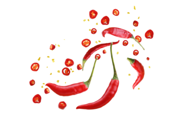 Floating red chili peppers with seeds and powder on white background.