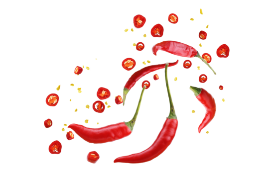Floating red chili peppers with seeds and powder on white background.