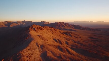 Naklejka premium Sunset over rugged mountains, vast landscape with warm hues lighting up rocky terrain, ideal for travel or nature themes.