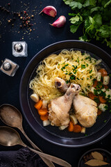 Broth - chicken soup with noodles and vegetables on black table
