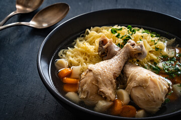 Broth - chicken soup with noodles and vegetables on black table