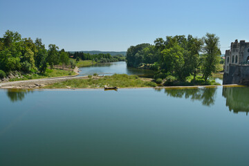 Obraz premium A dam on the Kupa River in Ozalj, Croatia, creates a calm pool of water reflecting the clear blue sky