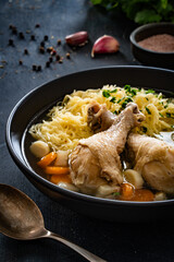 Broth - chicken soup with noodles and vegetables on black table