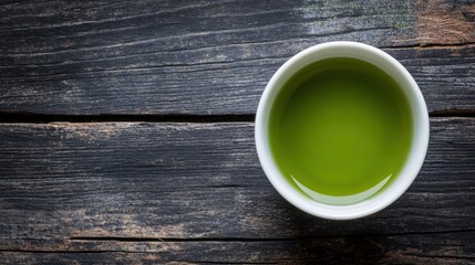 A single tea cup filled with matcha, placed on dark wood with space to add text in a promotional image.