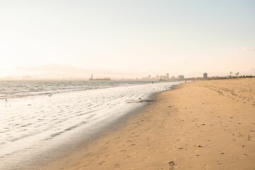 Serene beach scene at sunset with gentle waves and a distant city skyline in Los Angeles