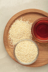 Sesame seeds and sesame oil on light background
