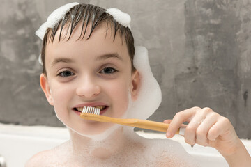 A young child with a happy expression, enjoying a bubble bath and holding a bamboo toothbrush. The image emphasizes cleanliness and sustainability, perfect for family and hygiene themes.