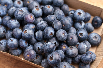 Fresh blueberries in paper container on wooden table. Fruits packaging concept. Top view. 