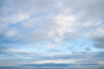 A serene view of a summer tranquil sky with soft white and grey clouds. A calming skyscape with flowing clouds in sunshine on a warm spring day. Beautiful bright cyan day with clouds landscape. 