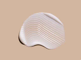 smear of creamy white texture cosmetic sample close up on beige background