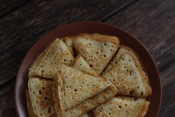 Bake openwork pancakes in a hole triangles on a plate on a dark background