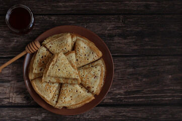 Baking openwork pancakes in a hole triangles on a plate on a dark background with honey