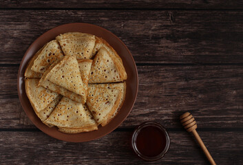 Baking openwork pancakes in a hole triangles on a plate on a dark background with honey