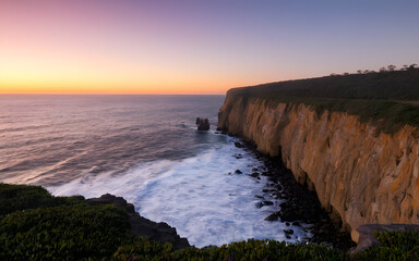Obraz premium Rocky cliff overlooking the ocean at dawn