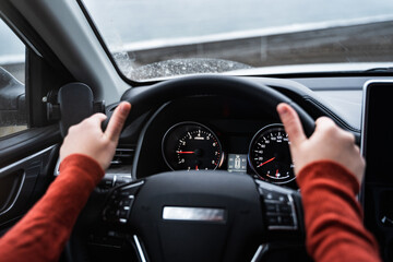 The dashboard in the car. An unrecognizable woman's hands on the steering wheel. Car travel. Road trip. Modern interior of a new car. Close-up view.