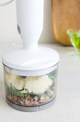 Roasted pistachios with basil, garlic and grated cheese in a blender bowl. The process of making pistachio pesto. Vertical orientation. Selective focus.