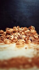 A delicate pile of mahogany shavings curls gracefully, showcasing the rich color and fine texture of the hardwood.