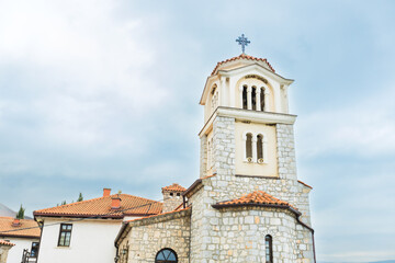 Majestic stone church with a bell tower, overlooking the serene waters of Lake Ohrid. The building weathered facade and traditional architecture reflect its rich history and cultural significance.