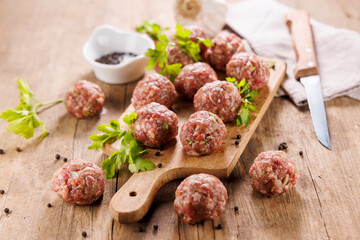 raw meatball with herb on wooden board