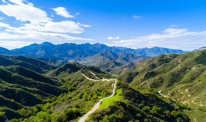 Naklejka premium Expansive Mountain Landscape with Lush Green Hills and Blue Sky
