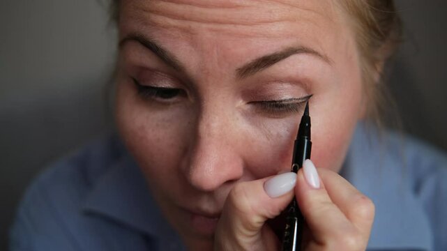 close-up of a woman doing eye makeup, she draws arrows with black eyeliner